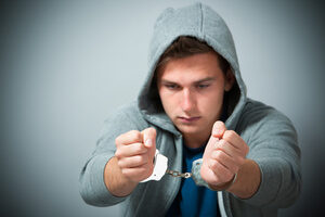 Man In Gray Hoodie Holding Out Handcuffed Wrists