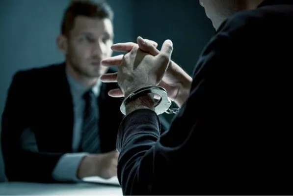 a man in handcuffs talking to an investigator