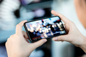 Cropped image of female hand holding smartphone and watching vid